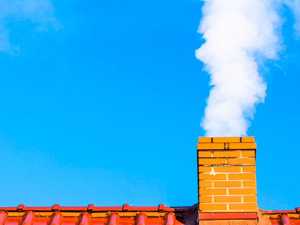 Modern house roof with chimney smoke, air pollution and smog in winter, ecological problems camini-in-rame