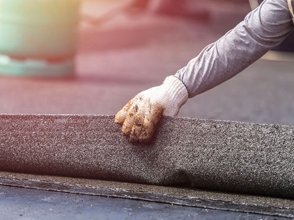 Group of worker installing tar foil on the rooftop of building. guaina-isolante-per-tetti