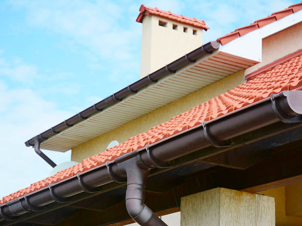 Rain gutters system on new house with chimney, red clay tiled r opere-in-lattoneria-correggio